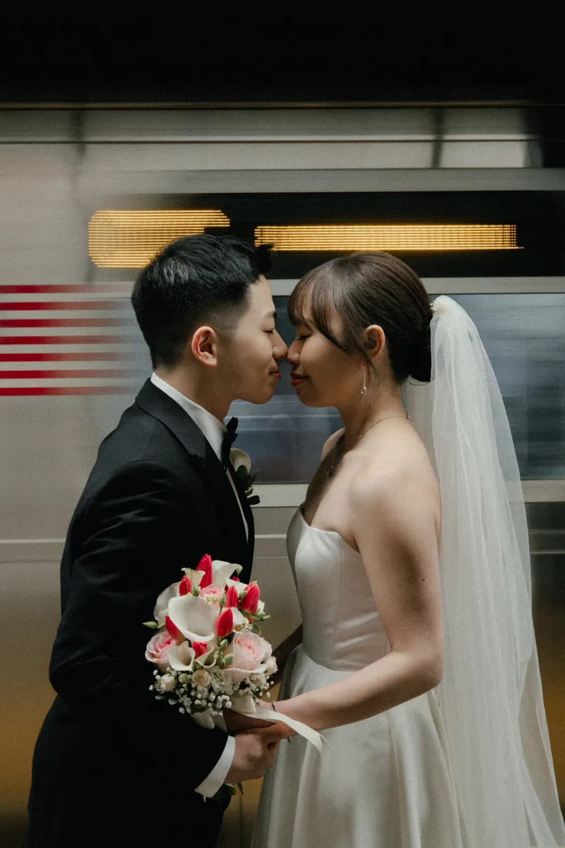 The couple sharing a kiss in front of a train.